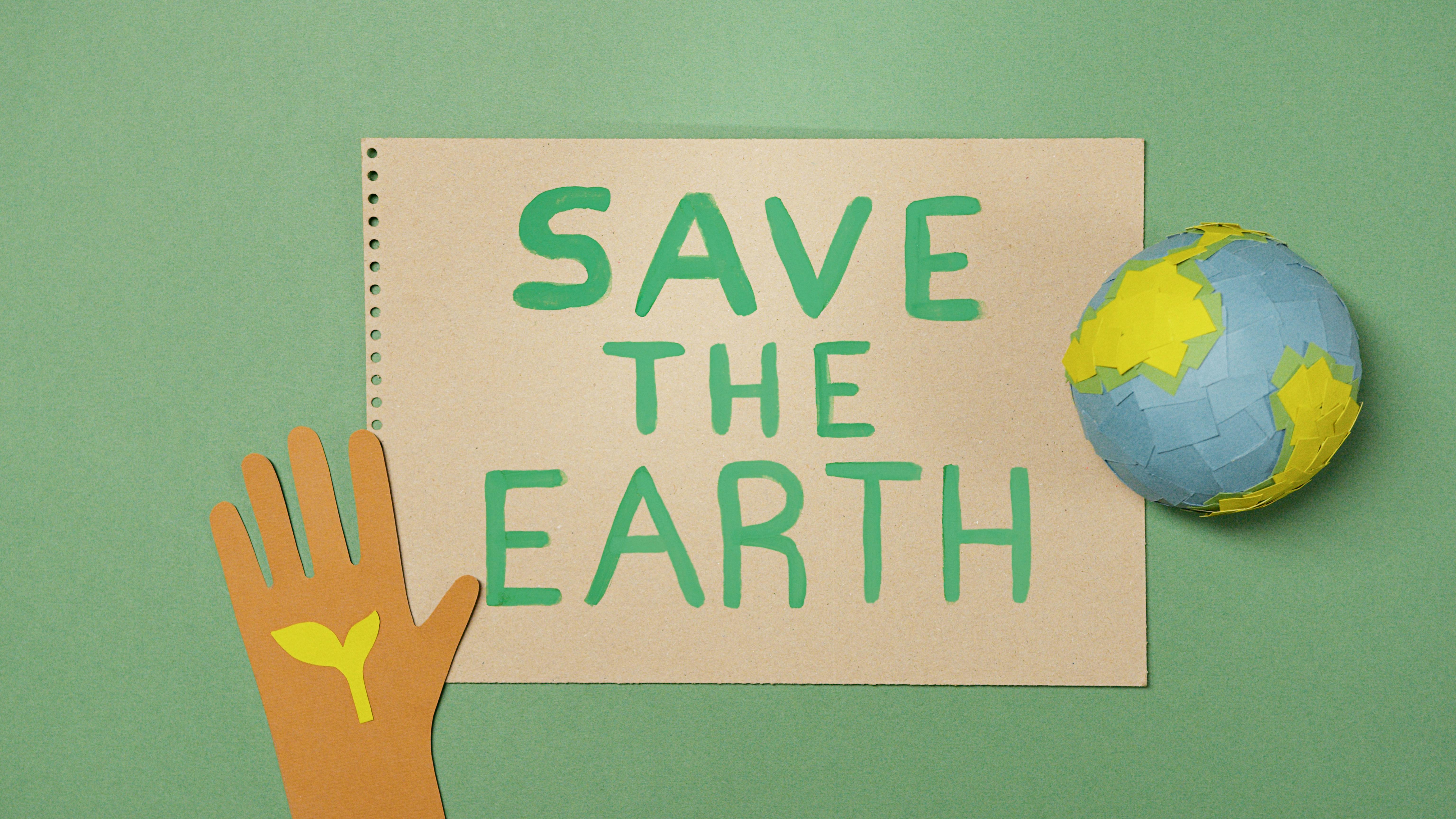 Paper with Save the Earth written on it. A hand and the earth is also featured.